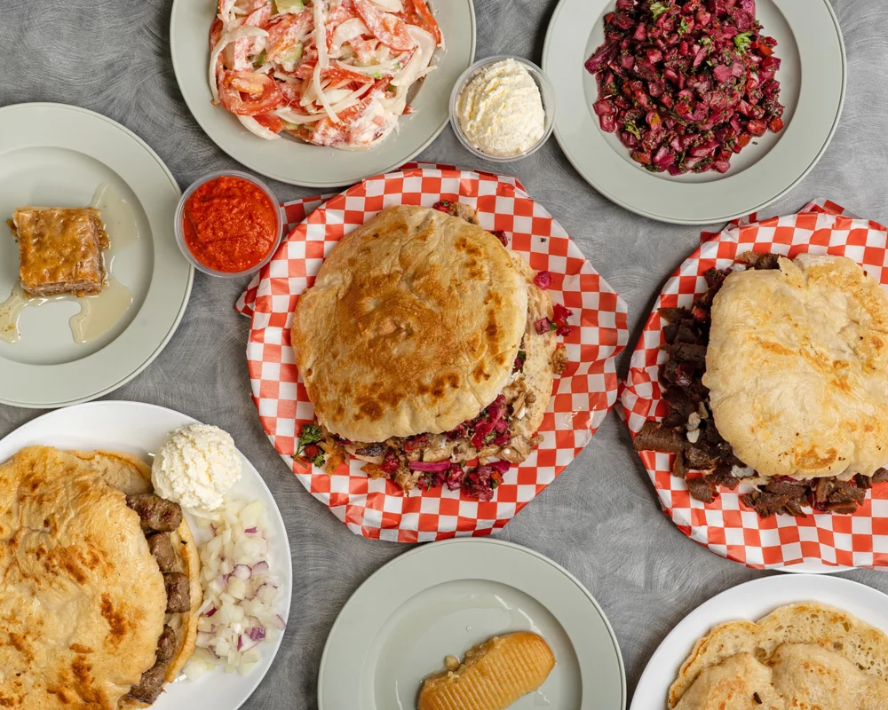 A table of chevapi, doner, salads, ajvar, kajmak and Balkan desserts
